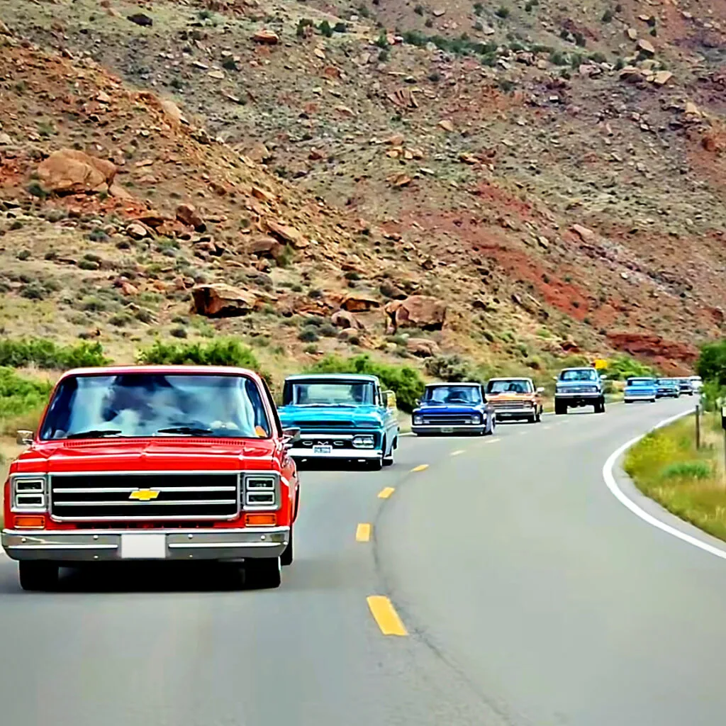 Convoy of classic Chevy and GMC pickups on a canyon road